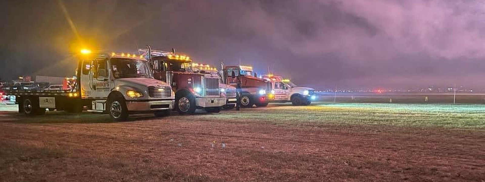 Mike's Wrecker Service trucks lined up at a night scene with light bars on