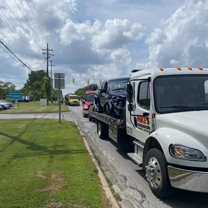Mike's flatbed hauling a car through town